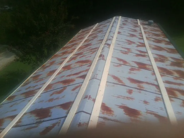 Rusted metal roof panels with new wood purlins before replacement — Storm Damage Roof Repair in Chestnut Ridge by Roofing Brothers