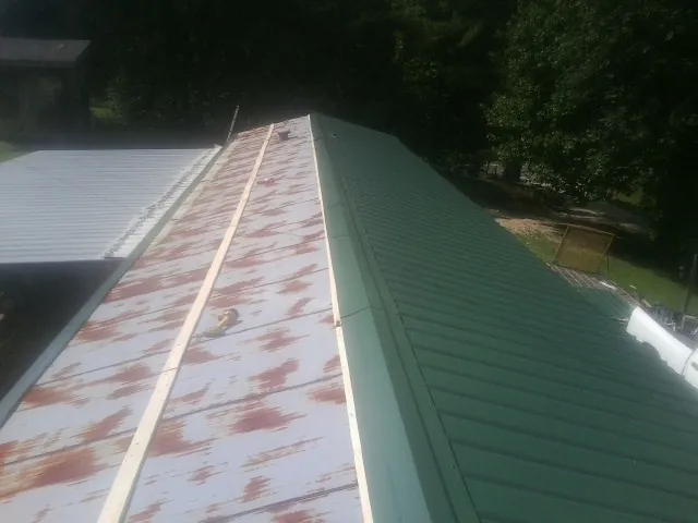 Old rusted panels beside newly installed green metal roofing — Wind Damage Roof Repair by Roofing Brothers in Chestnut Ridge