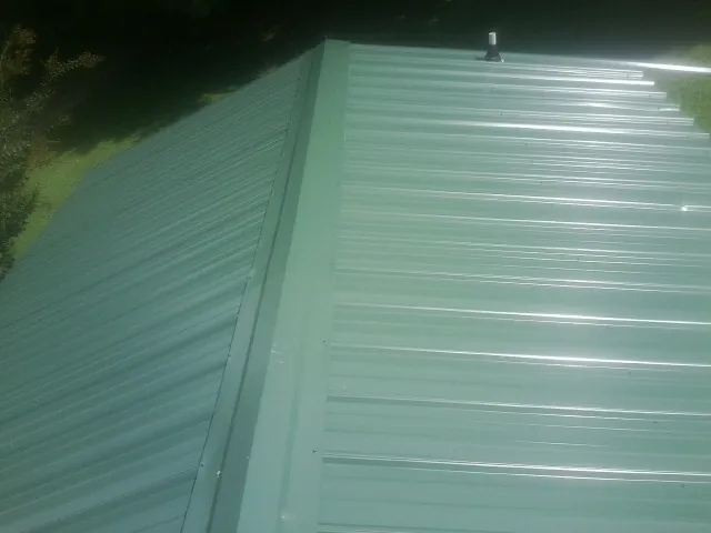 New green metal panels meeting at the ridge of a roof — Flat Roof Repair work by our crew in Chestnut Ridge