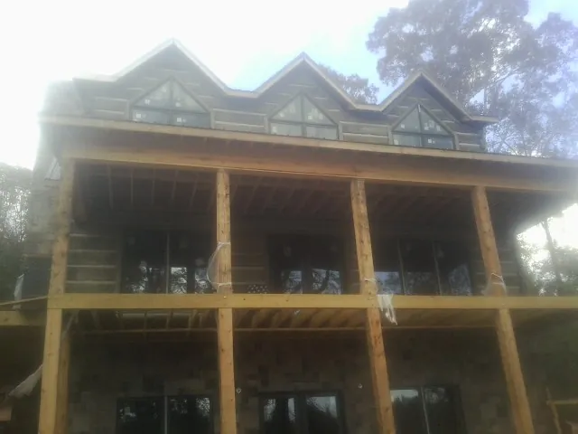 Dormers and porch framing on a large log home under construction — Roof Coating work by our crew in Chestnut Ridge