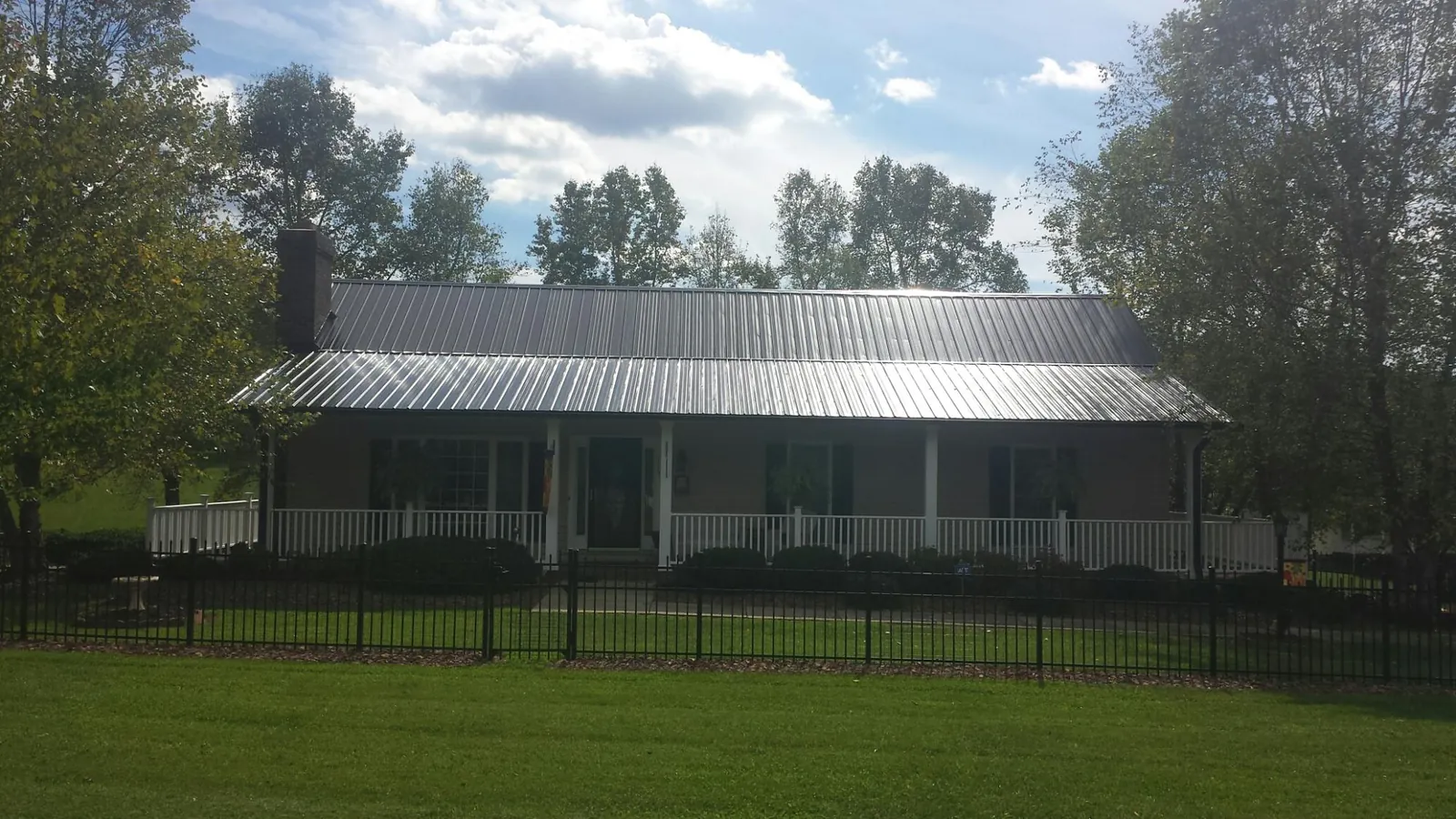 Gray metal roof on a brick ranch with a full width front porch — Gutter Guard Installation work by our crew in Chestnut Ridge