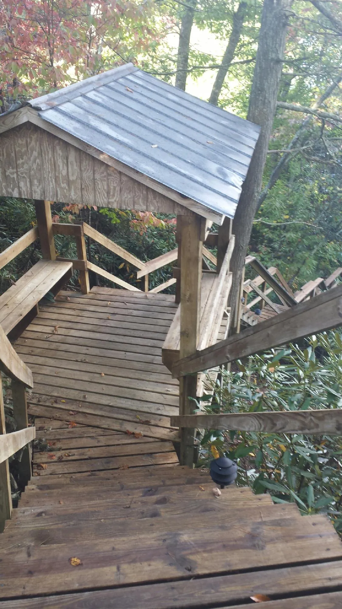 Metal roofed shelter over wooden steps on a wooded walkway — Skylight Repair & Installation work by our crew in Chestnut Ridge